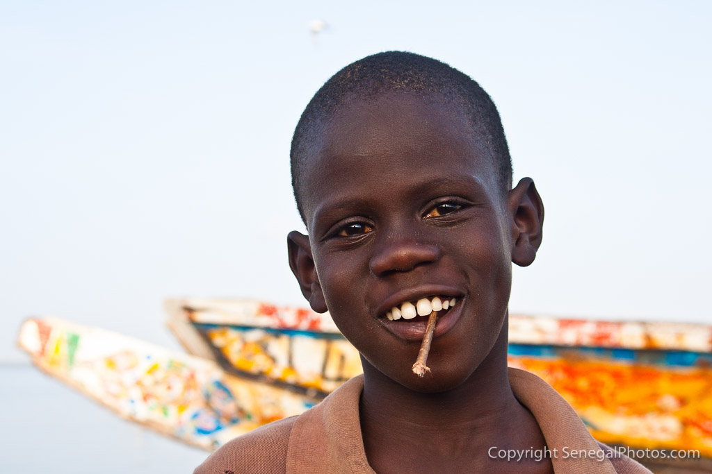 A smiling kid with an eco toothbrush on Senegal river shore in N'Dar Tout