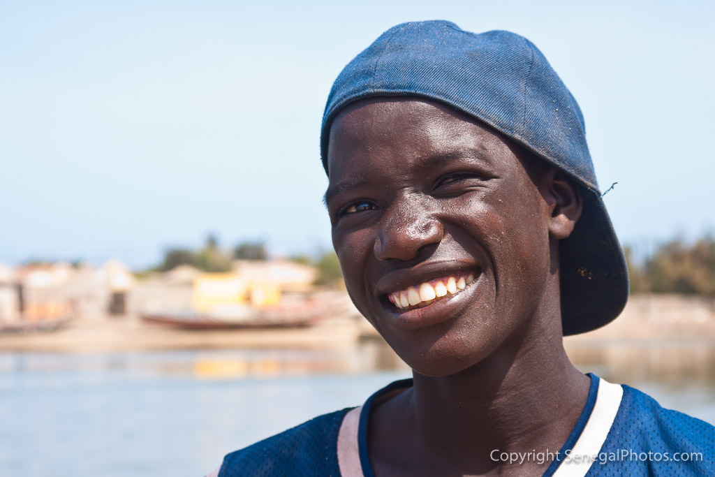 A young boatman operating shuttle across the Senegal river in pirogue boat ...